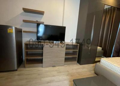 Compact bedroom with modern furnishings including wardrobe, TV, and refrigerator