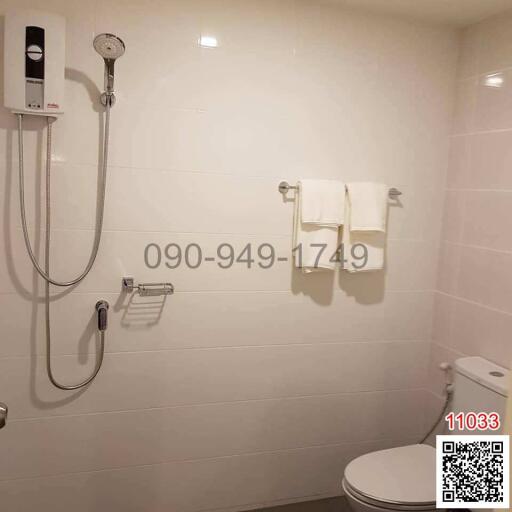 Modern bathroom with white tiles, shower, and toilet