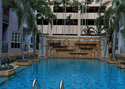 Swimming pool with stainless steel ladder and surrounding palm trees in a residential apartment complex