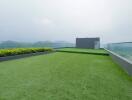 Spacious rooftop garden with green artificial grass and clear glass fence