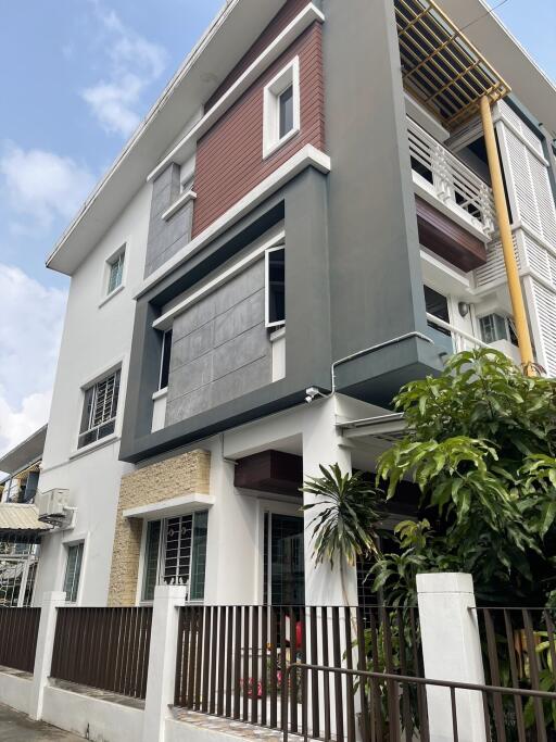 Modern multi-story residential building with a mix of gray and reddish-brown facade