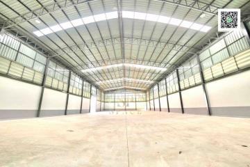 Spacious empty warehouse interior with high ceiling and natural lighting
