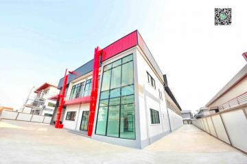 Modern two-story building with red accents and large glass windows under clear skies