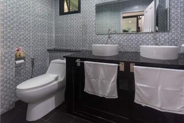 Modern bathroom with dual vessel sinks and mosaic tile walls