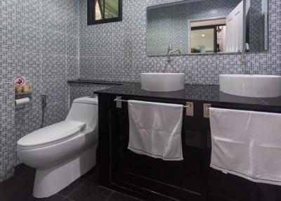 Modern bathroom with dual vessel sinks and mosaic tile walls