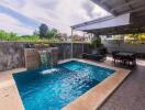 Private swimming pool with waterfall feature and outdoor dining area