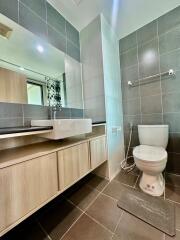 Modern bathroom with wooden vanity cabinet, toilet, and tiled walls