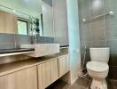 Modern bathroom with wooden vanity cabinet, toilet, and tiled walls