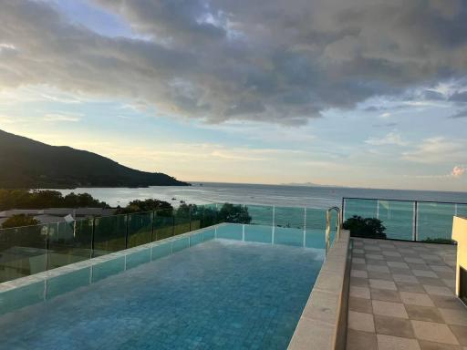 Outdoor infinity pool with ocean and mountain views at sunset