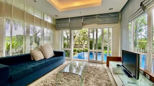 Spacious living room with large windows, natural light, and pool view