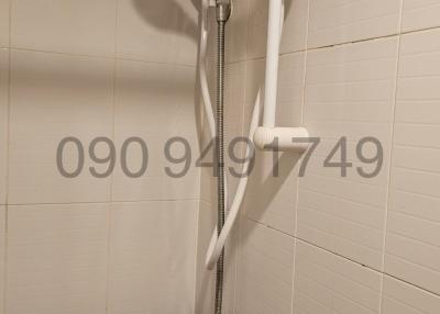 Electric shower unit with white wall tiles in bathroom