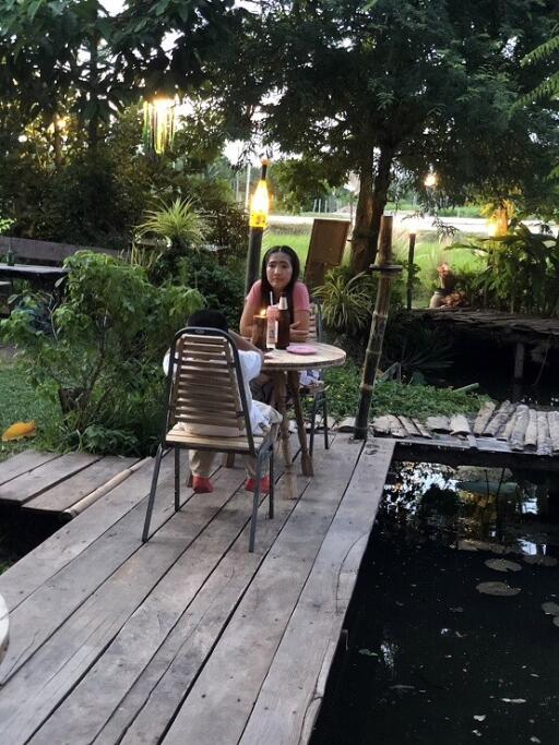 Woman sitting at a table in a scenic outdoor patio area by a pond