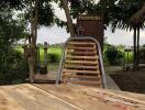 Wooden bridge leading to a rustic outdoor building surrounded by greenery