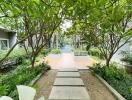 Paved pathway in a serene garden leading to modern residential buildings