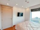 Modern bedroom with wooden floor, large window, and mounted television