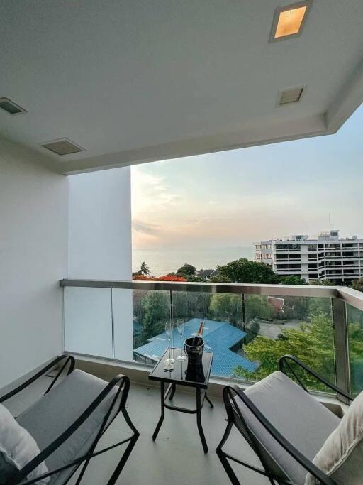 Cozy balcony with seating overlooking the ocean and sunset