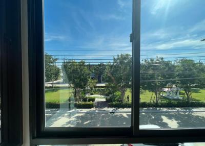 View from a building window overlooking a sunny neighborhood with trees and a clear blue sky