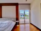 Spacious bedroom with hardwood floors and balcony access