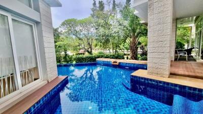 Luxurious outdoor swimming pool with blue mosaic tiles surrounded by trees