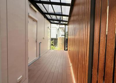 Spacious balcony with wooden flooring and partial glass roofing