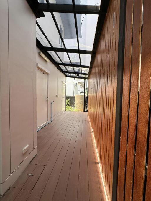 Spacious balcony with wooden flooring and partial glass roofing
