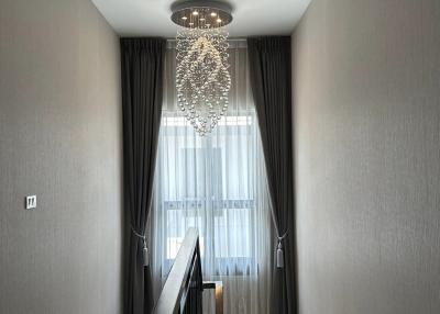Elegant hallway interior with a chandelier, dark curtains, and a wooden staircase