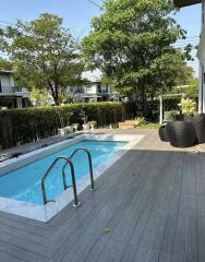 Swimming pool area with wooden deck and outdoor furniture in a residential property