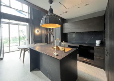 Modern kitchen with dark cabinetry and marble island under a large pendant light