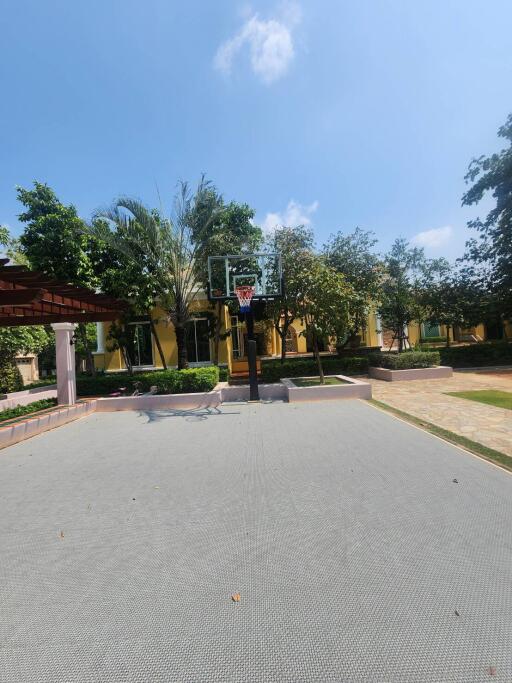 Basketball court in an outdoor community area with surrounding greenery and residential buildings in the background