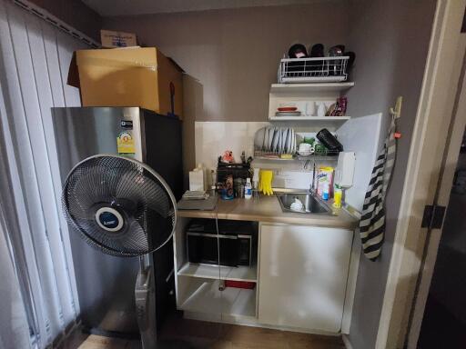 Compact kitchen space with essential appliances and storage shelves