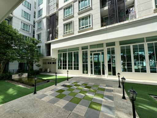 Front entrance of a modern apartment building with checkered tiles and green lawn