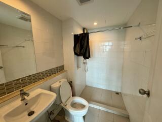 Spacious white tiled bathroom with toilet and shower