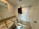 Spacious white tiled bathroom with toilet and shower