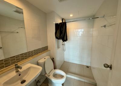 Spacious white tiled bathroom with toilet and shower