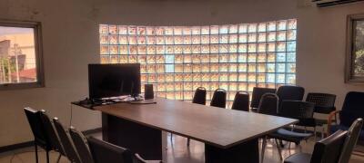 Spacious meeting room with large table, chairs, and television against a backdrop of glass block windows