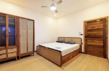 Spacious bedroom with wooden furnishings and flooring