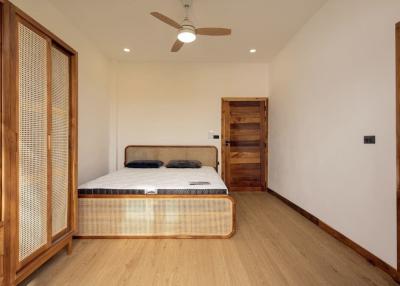 Spacious bedroom with wooden flooring and a large bed