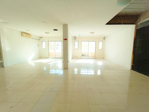 Spacious interior of an empty building with large windows and tiled floor