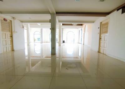 Spacious and brightly lit empty living space with glossy tiled flooring and multiple doors