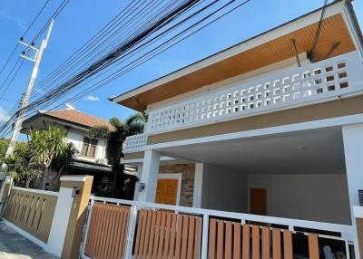 Modern two-story house with a balcony and carport under a clear blue sky