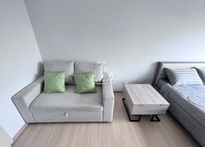 Modern living room interior with a comfortable sofa, coffee table, and a bed