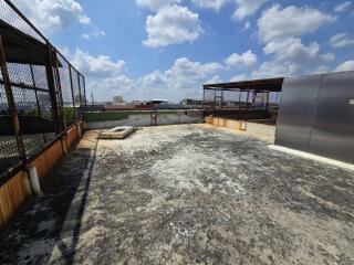 Spacious unadorned rooftop of a building with fencing and open sky