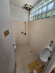 Compact bathroom with wall-mounted shower, ventilation window, and beige tiles