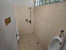 Compact bathroom with wall-mounted shower, ventilation window, and beige tiles