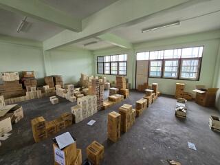 Spacious unfurnished storage room with large windows and multiple cardboard boxes