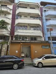 Multistory residential building with ground floor commercial space and parked cars in front