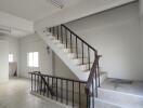 Wide angle view of a staircase area inside a property with white walls and tiled flooring