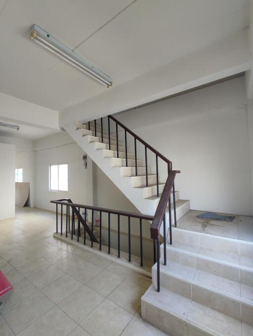 Wide angle view of a staircase area inside a property with white walls and tiled flooring