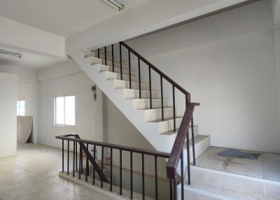 Wide angle view of a staircase area inside a property with white walls and tiled flooring