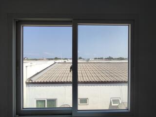 View from a window showing rooftops and a clear sky